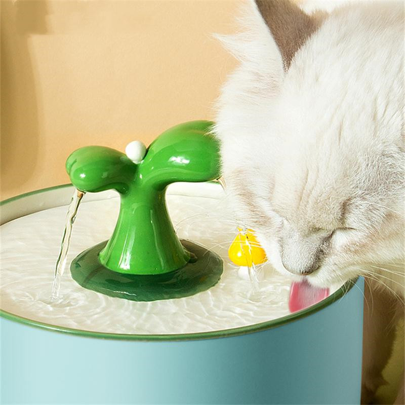 a white cat drinking water from a green faucet